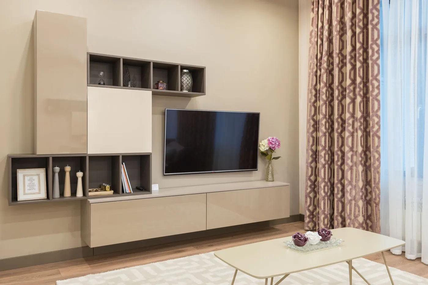 Modern living room with a wall-mounted television above a low cabinet, open shelving and a coffee table